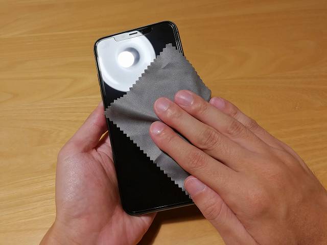 ガラスフィルムを貼り付け終わったiPhone 11 Pro Maxを拭いている画像